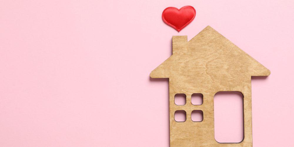 Beautiful heart and wooden house on pink background